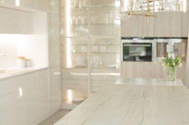 Bulanık boş mutfak, ahşap masa üstü ve beyaz modern iç mekan.