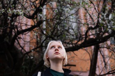 İlkbaharda çiçek açan ağaçların arka planında zarif genç bir kadın.