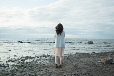 Mükemmel bir kadın dinleniyor ve baharda sahilde ayakta duruyor.