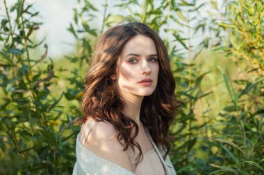 Temiz tenli, açık kahverengi saçlı, yeşil çimen arka planda güzel, sağlıklı, genç esmer kadın. Hava portresi.