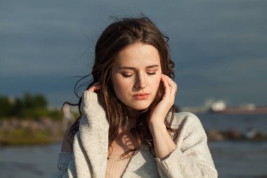 Bahar genç bayan esmer model deniz sahilinde. Makyajlı ve açık havada uzun siyah dalgalı saç stili olan bir kadın. Sükunet duygusu, seyahat, sezon ve tatil konsepti