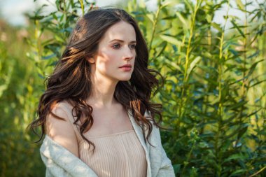 Taze, açık tenli, açık havada koyu kahverengi saçlı, yeşil çimen arka planda, hava portresi olan çekici, sağlıklı, genç bir esmer kadın.