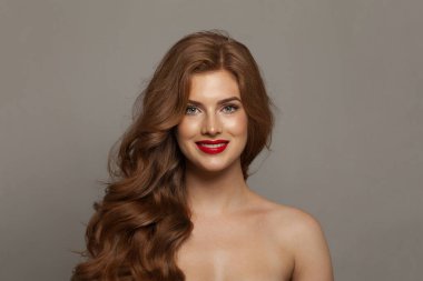 Çekici, genç, mutlu, doğal makyajlı, temiz, sağlıklı ciltli ve beyaz arka planda uzun saçlı bir kadın modeli. Kıvırcık, saç bakımı, cilt bakımı ve yüz bakımı konsepti