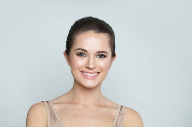 Çekici, sağlıklı, güzel ciltli, beyaz arka planda sevimli bir gülümsemesi olan, stüdyo portresi olan bir kadın. Yüz bakımı, cilt bakımı ve kozmetik konsepti