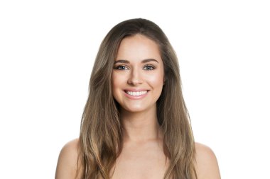 Sağlıklı saçlı, makyajlı ve beyaz stüdyo duvarına poz veren parlak ciltli gülümseyen genç bir bayan model. Yüz bakımı, kozmetoloji, saç bakımı ve güzellik kadın konsepti