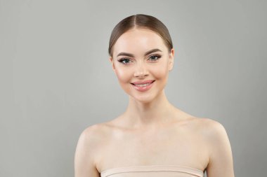 Güzel cildi ve beyaz arka planda sevimli gülüşü olan muhteşem, sağlıklı model bir kadın, stüdyo portresi. Yüz bakımı, cilt bakımı ve kozmetik konsepti