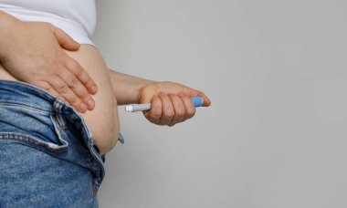 Midesine enjeksiyon yapan bir kadın. Beyaz arkaplanda beyaz arkaplanda ağırlık kaybı için kullanılan Semaglutide veya insülin enjeksiyon kalemi diyabet ilacı