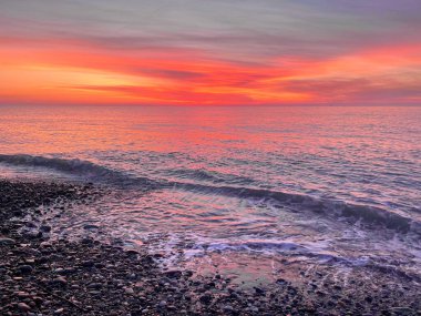 Bulutlu ve deniz sahilli parlak gün batımı gökyüzü. Doğa yolculuğu arka planı