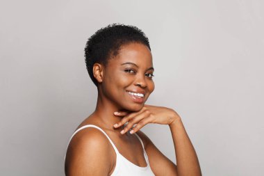 Beyaz arka planda koyu tenli neşeli, sağlıklı bir bayan. Reklamcılık, ürün yerleştirme, ilaç ve tedavi kavramı