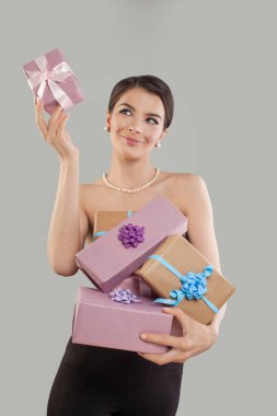 Mutlu esmer kadın hediye kutusunu tutuyor ve beyaz arka planda pembe hediyeye bakıyor..
