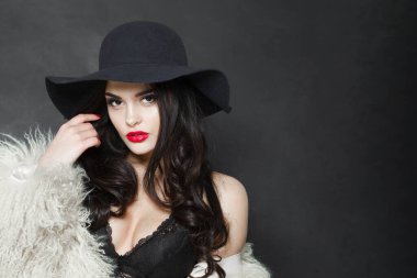 Şehvetli, genç, yetişkin bir kadın model. Parlak makyajlı ve uzun dalgalı saçlı. Mavi şapkalı.