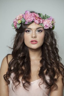 Temiz, taze tenli, dalgalı, uzun saçlı, çiçek çelenkli, güzel bir kadın.