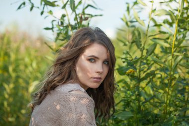 Temiz cilt, doğal makyaj ve kıvırcık saç stili yeşil çimen arka plan, açık hava portresi