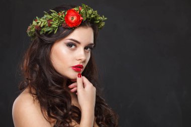 Çiçekli başlıklı mutlu genç kadın siyah arka planda dikilirken kameraya bakıyor..