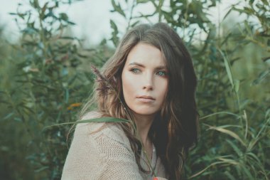 Uzun dalgalı saç stili ve doğal makyajlı, açık hava güzelliği portresi olan çekici, genç, yetişkin model bir kadın.