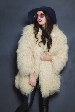 Makyajlı, uzun kıvırcık saçlı, mavi arka planda poz veren mükemmel bir esmer kadın. Moda güzellik stüdyosu resmi.