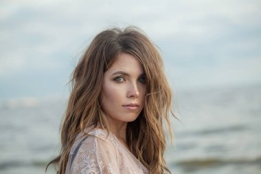 Rüzgarlı kahverengi saçlı, açık havada yürüyen genç ve güzel bir bayan model.