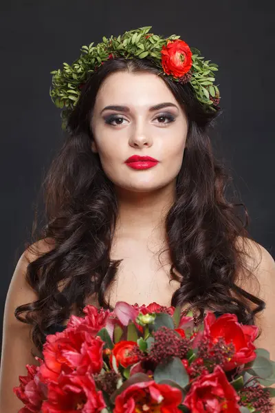 Kırmızı çelenkli ve moda makyajlı güzel bir kadın. Çiçek saç stili, kırmızı dudaklar.