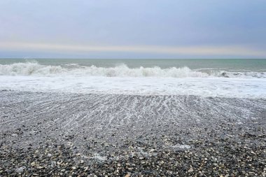 Denizde soğuk bir sabah. Deniz dalgası ve taş plajı, seyahat arka planı.