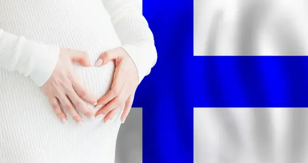 stock image Demographics, pregnancy and love baby in Finland concept. Pregnant woman making heart against her stomach on Finnish flag background. 