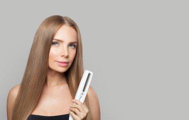 Beyaz arka planda düz saçlı model esmer bayan düz demiri tutuyor. Kadın güzelliği, kuaför, saç bakımı, kozmetik ve stil konsepti