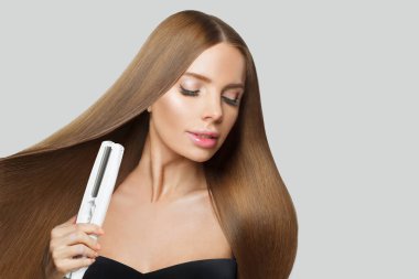Beyaz arka planda saç düzleştirici kullanan çekici manken kadın. Harstyle, saç bakımı, güzellik salonu ve tedavi konsepti