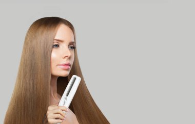 Uzun saçlı hoş bir kadın düz saç maşası kullanıyor ve saç stili, güzellik, bakım ve moda konsepti yapıyor.