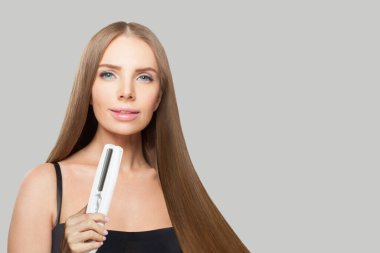 Güzel görünümlü esmer kadın düz saçlı beyaz arka planda düz ütü tutuyor. Kadın güzelliği, kuaför, saç bakımı, kozmetik ve stil konsepti