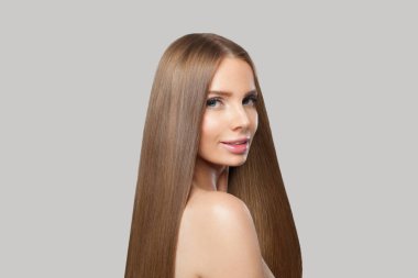 Güzel kadın yüzü. Gri arka planda uzun kahverengi saçlı ve makyajlı bir model. Güzellik, saç bakımı ve kozmetik portre