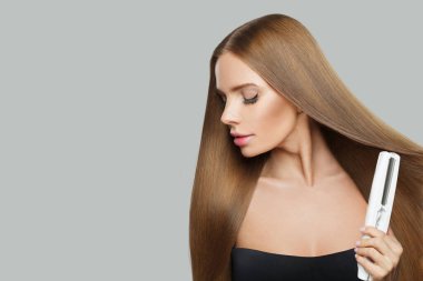Beyaz arka planda saç düzleştirici kullanan zarif model kadın. Harstyle, saç bakımı, güzellik salonu ve tedavi konsepti
