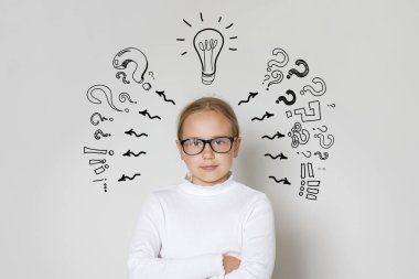 Ampulü ve beyaz arka planda soru işaretleri olan meraklı bir kız çocuğu. Eğitim ve fikir kavramı