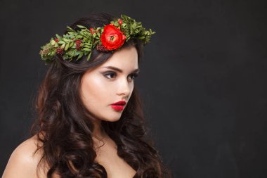 Parlak saçlı, makyajlı ve siyah arka planda bahar çiçeği olan zarif, sağlıklı bir kadın model.