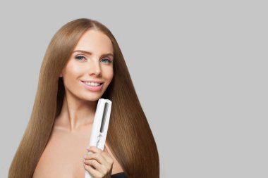 Kahverengi düz haistyle portresi olan güzel bir manken. Gri stüdyo arka planında elinde ütüyle sevimli bir kadın.