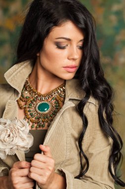 Sanat stüdyosunda poz veren esmer kadın. Uzun kıvırcık saçlı ve yeşil arka planda makyajlı genç bayan.