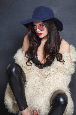 Kırmızı dudaklı, uzun dalgalı saçlı, mavi şapkalı, esmer, yakışıklı bir kadın.