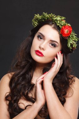 Parlak saçlı, makyajlı ve siyah arka planda bahar çiçeği olan neşeli, sağlıklı bir kadın model.