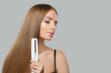 Kahverengi düz haistyle portresi olan çekici bir manken. Gri stüdyo arka planında elinde ütüyle sevimli bir kadın.