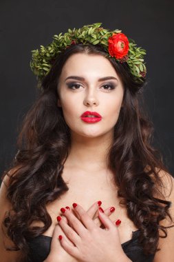 Parlak saçlı, makyajlı ve siyah arka planda bahar çiçeği olan sağlıklı bir kadın modeli.