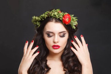 Parlak saçlı, makyajlı ve siyah arka planda bahar çiçeği olan hoş, sağlıklı bir kadın model.