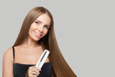 Kahverengi saçlı esmer kadın düz saçlı beyaz arka planda düz ütü tutuyor. Kadın güzelliği, kuaför, saç bakımı, kozmetik ve stil konsepti