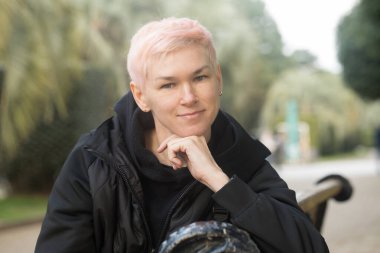 Parktaki bankta oturan gülümseyen olgun kadın