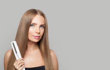 Uzun saçlı güzel bir kadın düz saç maşası kullanıyor ve saç stili, güzellik, bakım ve moda konsepti yapıyor.