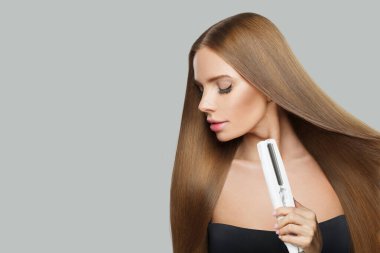 Uzun kahverengi düz saç stili, düz demiri olan model bir kadının stüdyo portresi. Kuaför, güzellik bakımı, saç düzleştirme, makyaj ve stil.