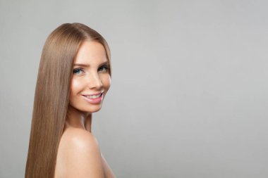 Modern makyajlı ve uzun düz saç stili beyaz stüdyo arka planında duran mutlu genç kadın modeli.