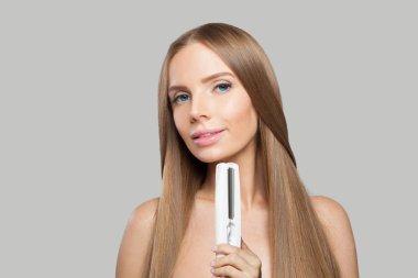 Beyaz arka planda düz saçlı, güzel esmer kadın ütüyü düz tutuyordu. Kadın güzelliği, kuaför, saç bakımı, kozmetik ve stil konsepti