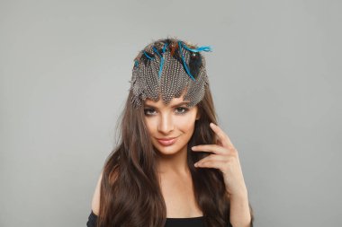 Sağlıklı, uzun, dalgalı saç stili, modaya uygun makyaj ve kafasında saç kılı aksesuarları olan çekici bir kadın model. Kameraya bakıyor. Moda güzellik portresi.