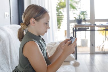 Akıllı telefonu evde tutan güzel bir çocuk. Oynayan, öğrenen ya da evde telefon cihazıyla video izleyen tatlı bir kız. Teknoloji, iletişim ve çocukluk kavramı