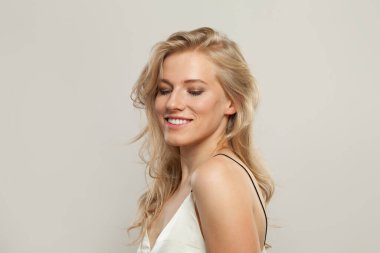 Açık tenli, yumuşak makyajlı, sağlıklı saçlı ve doğal duygusal yüz ifadesi olan güzel, genç bir bayan model. Beyaz arka planda sarışın kadın.
