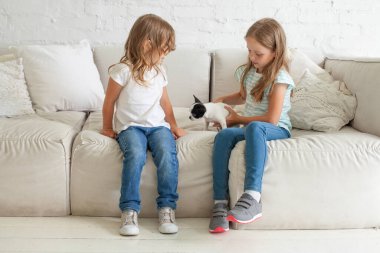 Evde köpek besleyen küçük kız kardeşler.