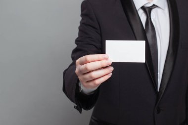 Beyaz kartvizit tutan takım elbiseli bir adam. Profesyonellik ve resmiyet kavramı